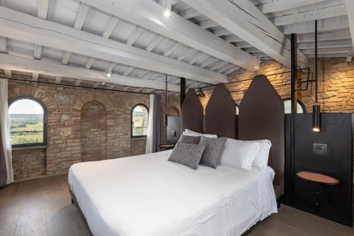 a bedroom with a white bed and a brick wall at Suite Deluxe Torre in San Gimignano