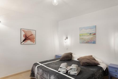 a bedroom with a bed with two pairs of slippers at Casa Paula - 25 in Arinaga