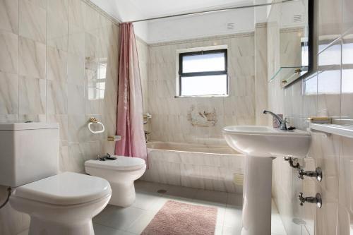 a white bathroom with a toilet and a sink at Vivenda Ribeiro - B in Lagos