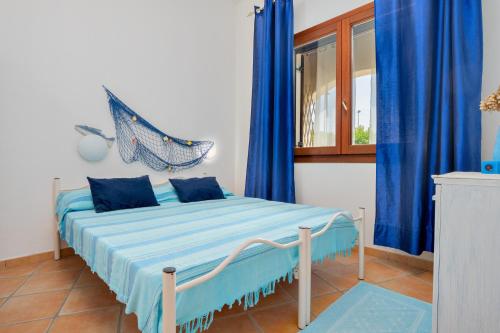 a bedroom with a bed with blue curtains and a window at Il Giardino di Viola in Porto Ottiolu