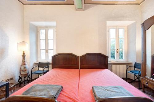 a bedroom with a bed with red sheets and windows at in Villa Belli in Miasino