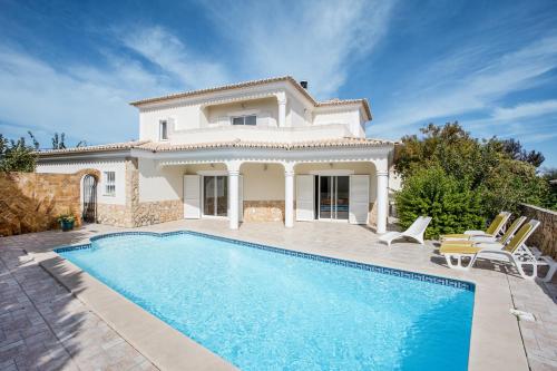 a villa with a swimming pool in front of a house at Casa das Romanzeiras in Carvoeiro