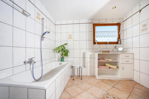 a white bathroom with a tub and a sink at Paulas Ferienwohnung Koenigscard in Füssen