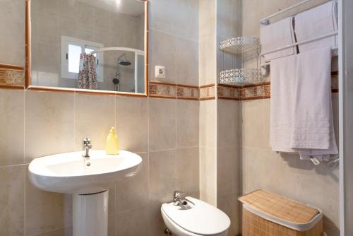 a bathroom with a sink and a mirror and a toilet at Los Olivos in Barbate