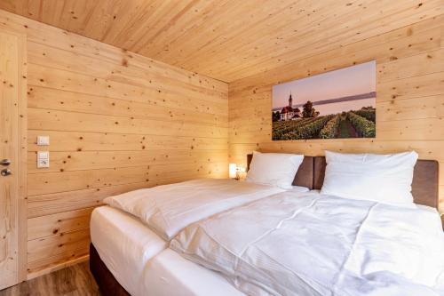 a bedroom with a white bed in a wooden room at Chalets Jettweiler in Stockach