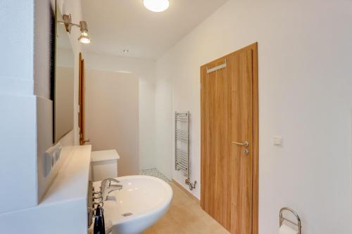 a bathroom with a white sink and a wooden door at Ferienwohnung Familie Arnhofer in Waal