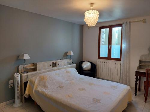 a bedroom with a large bed and a chandelier at Le Vieil Olivier in Sahune