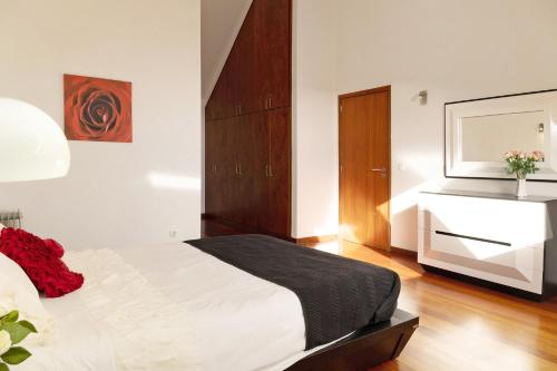 a bedroom with a bed with a dresser and a fireplace at Villa Aurélio in Campanário