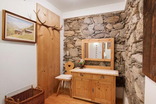 a bathroom with a vanity and a stone wall at Bachguthof in Silandro