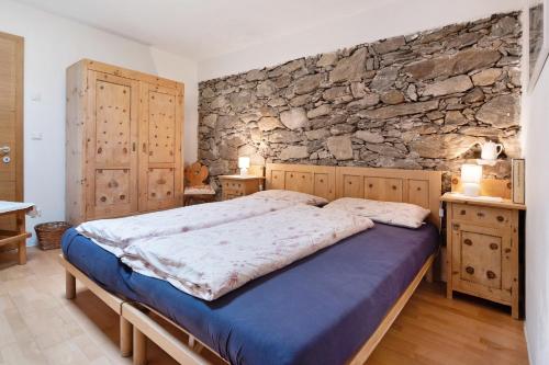 a bedroom with a bed and a stone wall at Bachguthof in Silandro