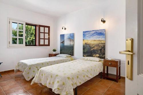 a bedroom with two beds and a painting on the wall at El Charco Azul in Charco del Palo