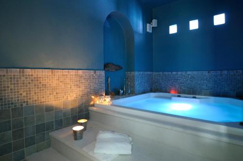 a blue bathroom with a tub with candles and lights at Villa St' Astra in Koufonisia