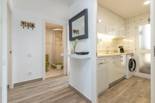 a white kitchen with a sink and a mirror at La Escala in L'Escala