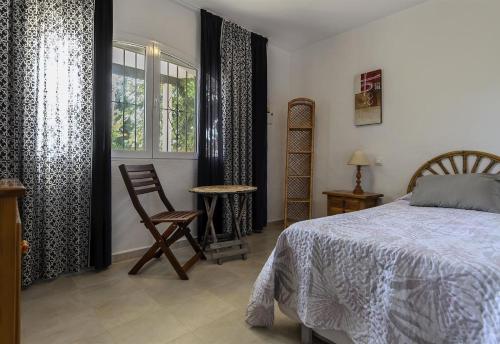 a bedroom with a bed and a chair and a window at Vista Bahía in Moraira