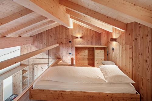 a bed in a room with wooden walls at Noah Suites in Vigo di Fassa