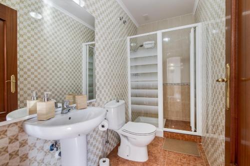 a bathroom with a toilet and a sink and a shower at Villa Marília in Ayamonte