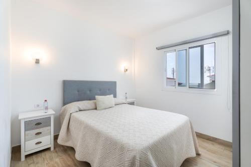a white bedroom with a bed and a window at Casa Mar Azul in Frontera