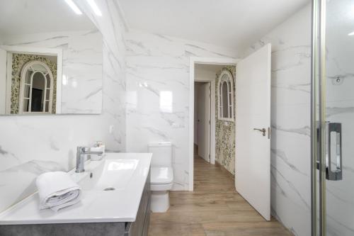 a white bathroom with a sink and a toilet at Casa Mar Azul in Frontera