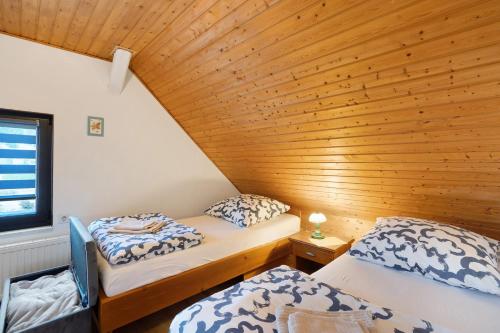 two beds in a room with a wooden ceiling at Ferienhaus Schmalzgrube in Jöhstadt