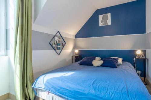 a bedroom with a blue bed with two pillows at La bonne descente in Fouesnant