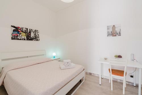 a white bedroom with a bed and a desk at Disiu Case Vacanza - Balestrate in Balestrate