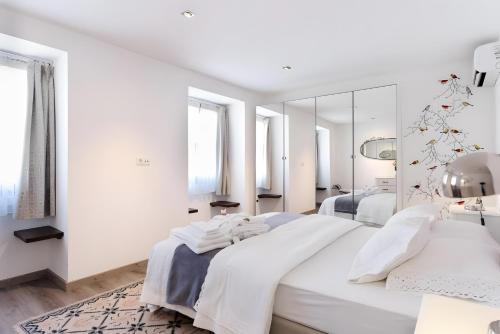 a white bedroom with two beds and a mirror at Casa Douro Janja in Armamar