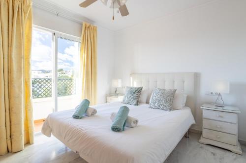 a bedroom with a white bed with pillows and a window at Casa Chloe in Nerja