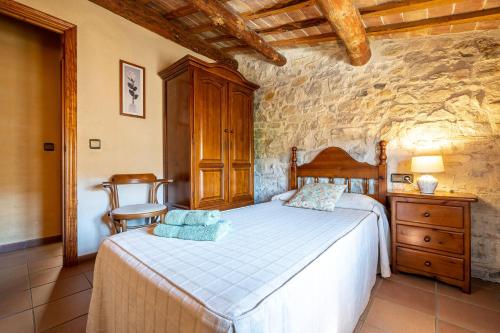 a bedroom with a bed and a stone wall at El Clos 3 in Conesa