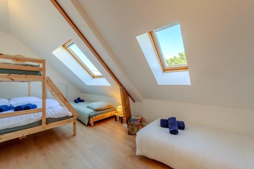 a attic bedroom with two bunk beds and windows at Maison Stoubenn in Kerlouan
