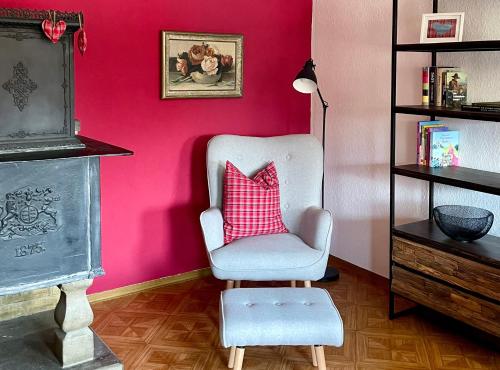 a pink room with a chair with a pink pillow at Ferienwohnungen Im Eugenhaus in Rosenfeld