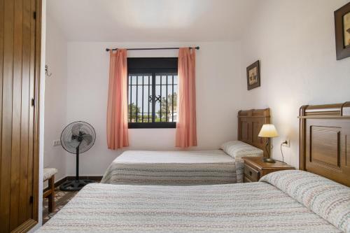 a bedroom with two beds and a window at Casa Carmelo 2 familias o parejas in Conil de la Frontera