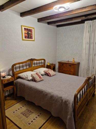 a bedroom with a wooden bed with two pillows at Mamie Krema in Boresse-et-Martron