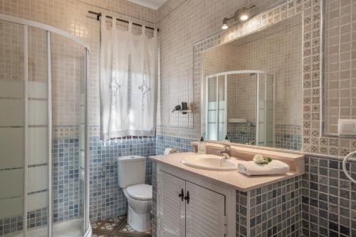 a bathroom with a sink and a toilet and a mirror at Casa Carmelo 2 familias o parejas in Conil de la Frontera