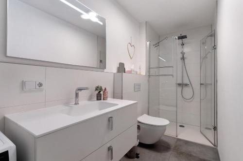 a white bathroom with a sink and a shower at Kölsch-Marie in Durbach