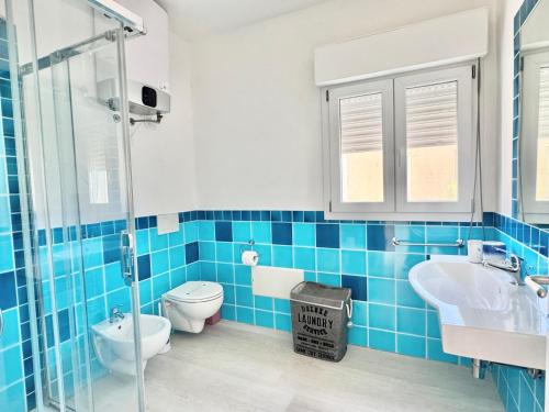 a blue tiled bathroom with a toilet and a sink at Casa Greis in Stintino