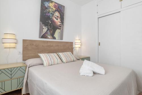 a bedroom with a bed with a painting on the wall at Apartamento Playa Regla in Chipiona