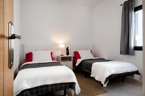 two beds in a room with white walls and red pillows at Apartamento La Estrella I in Playa Honda