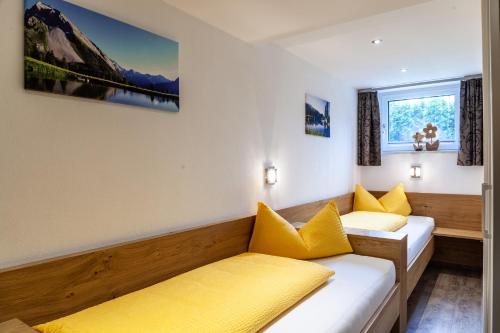 a room with two beds with yellow pillows at Haus Alpenheim Apartment 2 in Tux