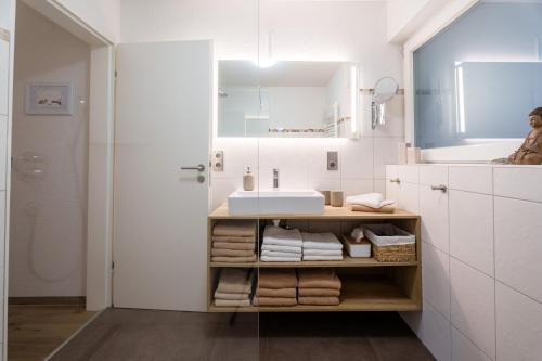 a white bathroom with a sink and towels at Sonnenterrasse 9 in Fischerbach