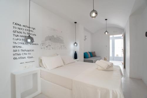 a white bedroom with a white bed and a wall with writing at Helmos Cozy Studio in Naxos Chora