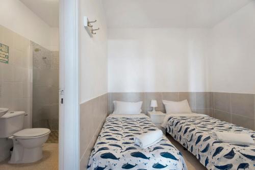 two beds in a room with a toilet and a bathroom at Apartamentos Playa Azul - 2 in Vallehermoso