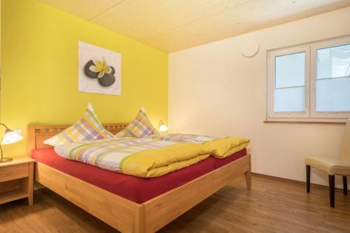 a bedroom with a bed with yellow walls and a window at Ferienhof Weber Ferienwohnung Buche in Neukirch