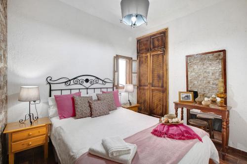 a bedroom with a large white bed with pink pillows at Finca Las Carmenes in Icod de los Vinos