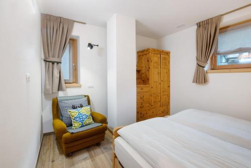 a bedroom with a bed and a chair at Chalet Pieri - Appartamento Temelin in Bormio