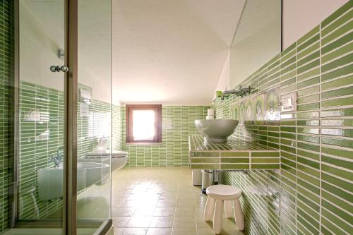 a green bathroom with a sink and a toilet at Villa delle Palme in Cecina
