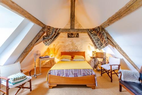 a bedroom with a bed and chairs in a attic at Chambres d'hôtes Exotique in Saint-Jory-las-Bloux
