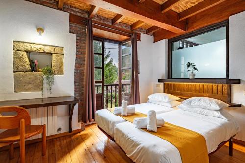 two beds in a room with a large window at Casa Florenta G2 in Cangas de Onís
