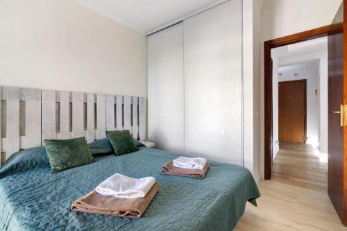 a bedroom with a green bed with towels on it at Barbecue and Beach – 200m away in Armação de Pêra