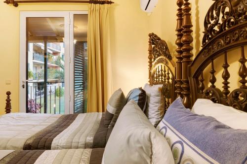 a bedroom with a large wooden bed and a window at Palheiro Residence Vista Mar in Funchal