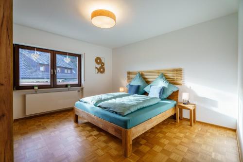 a bedroom with a bed with blue pillows and a window at Brandenkopfblick in Oberharmersbach